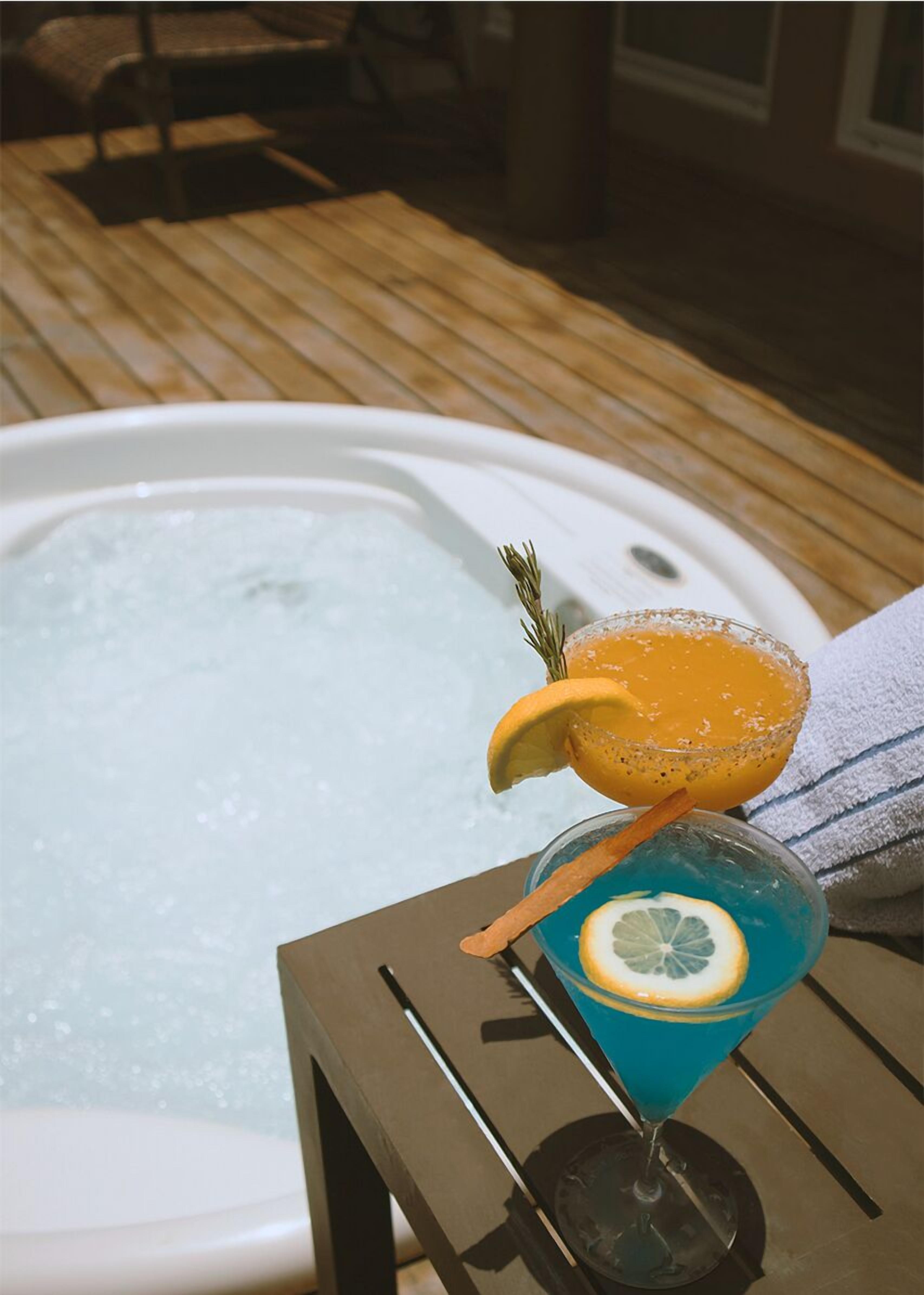 Un jacuzzi con dos cócteles sobre una mesa de madera.
