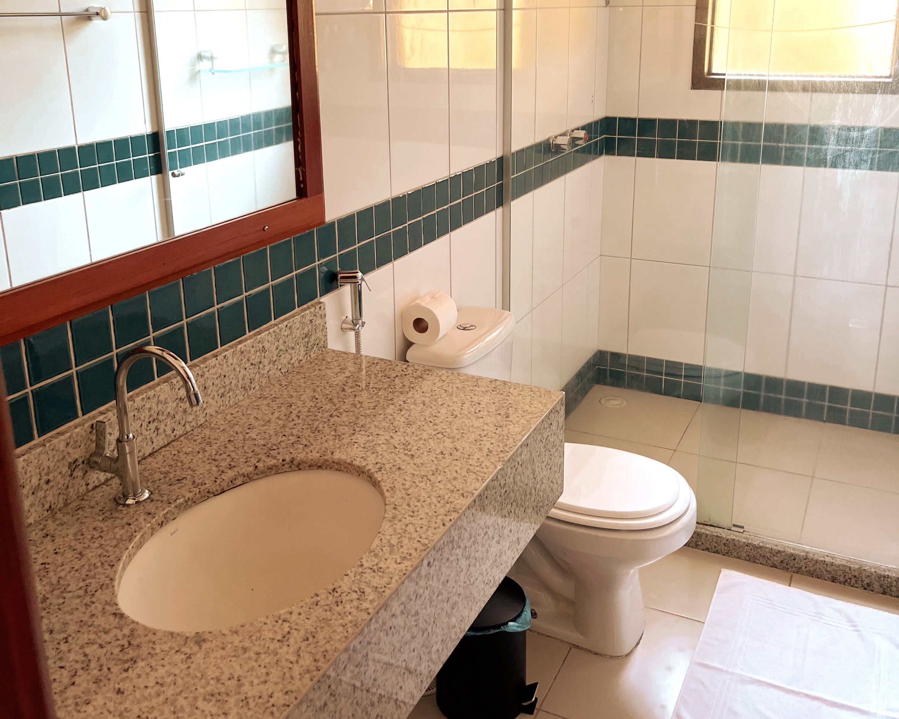 A bathroom with a granite countertop sink, a toilet, and a mirror.