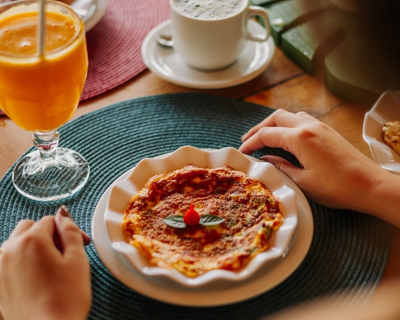 Une table mise pour le petit-déjeuner, avec une assiette de nourriture, un verre de jus d’orange et une tasse de café.