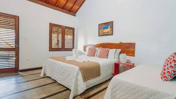 A hotel room with two beds, a wooden headboard, a painting on the wall, and a red nightstand.