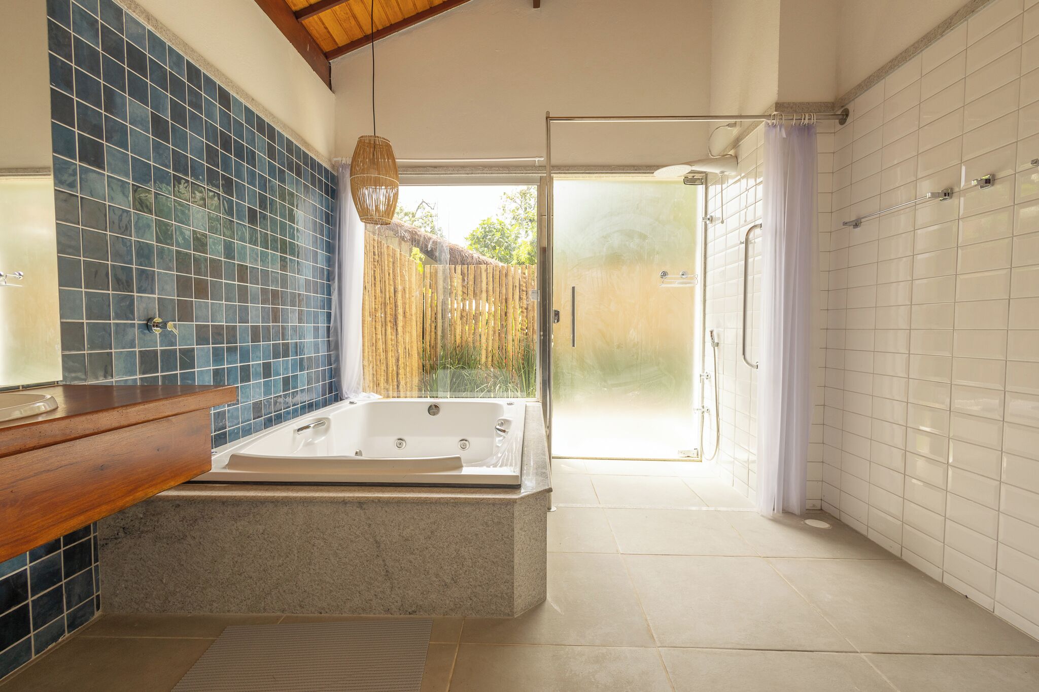 A bathroom with a bathtub, a wooden vanity, and a glass shower enclosure.
