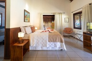 Relax in comfort with a large bed, a cozy seating area, and a convenient nightstand with a lamp.