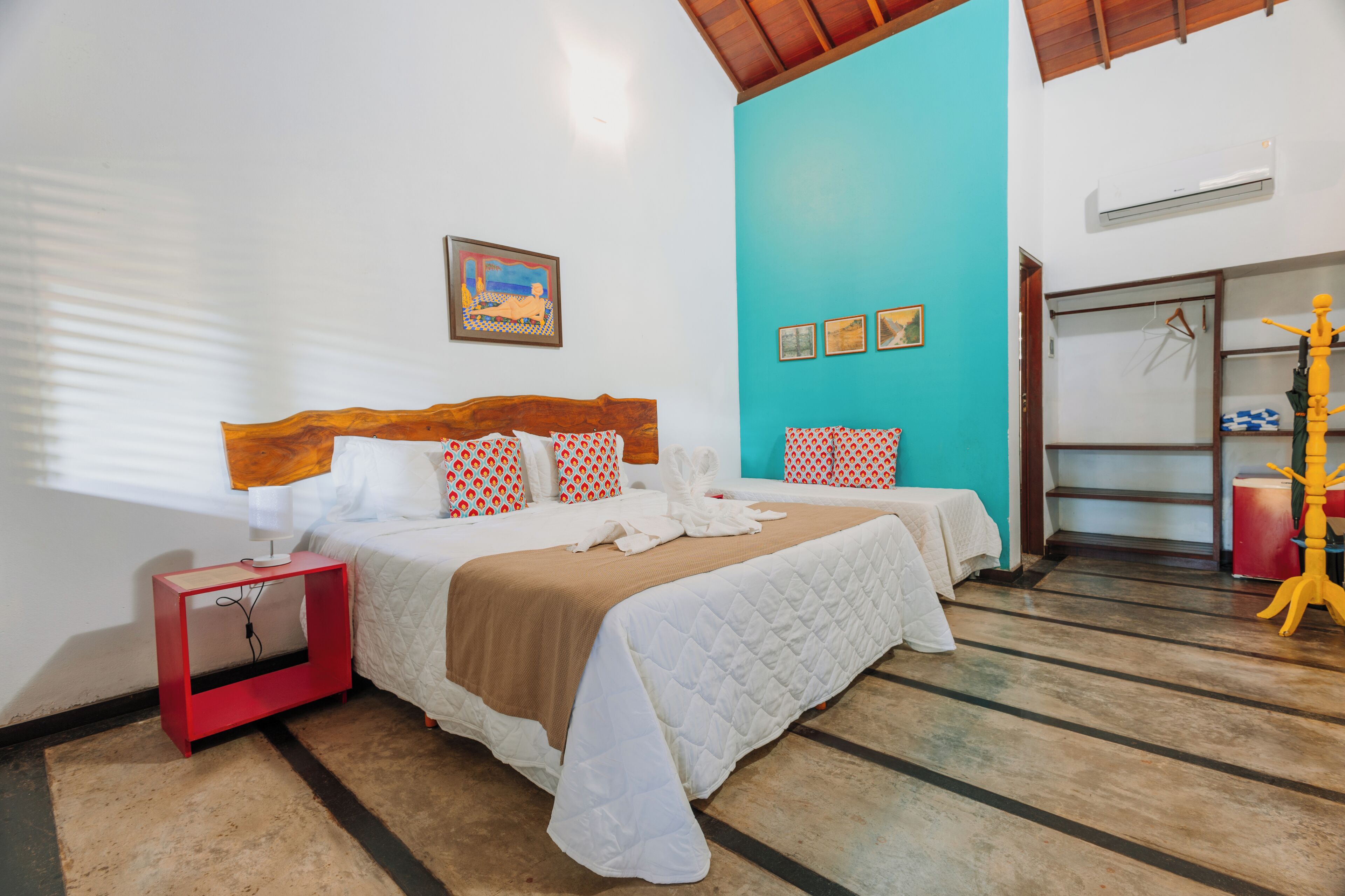 A bedroom with a bed, a nightstand, a wall-mounted shelf, and a door.