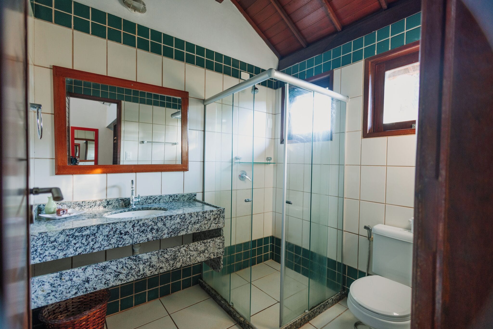 Une salle de bain avec une douche à parois de verre, un lavabo doté d’un plan de toilette en marbre et des toilettes.