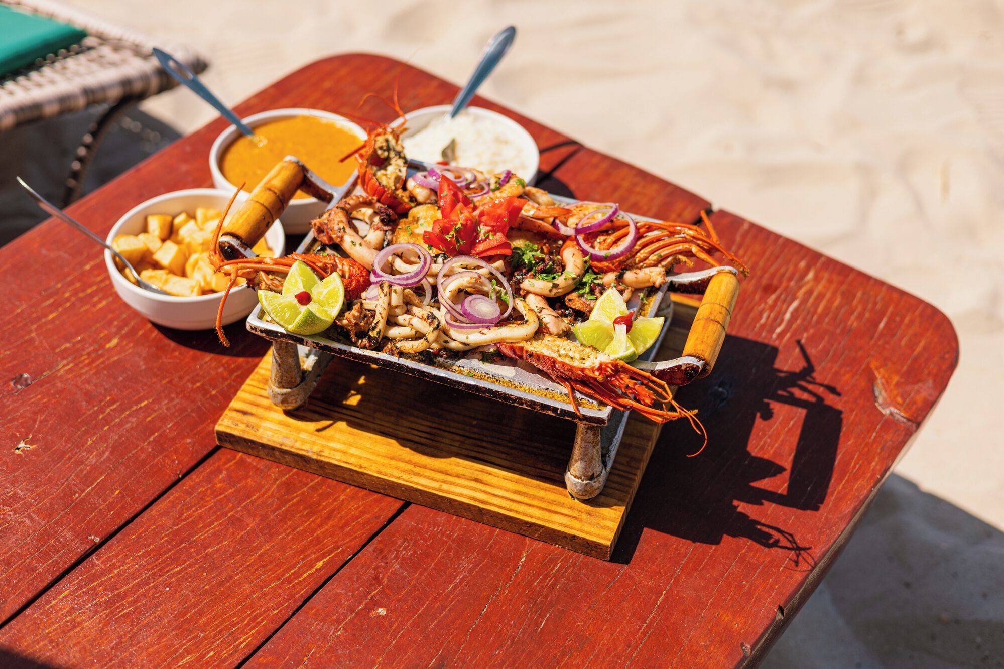 A seafood platter on a wooden table with a beach in the background.