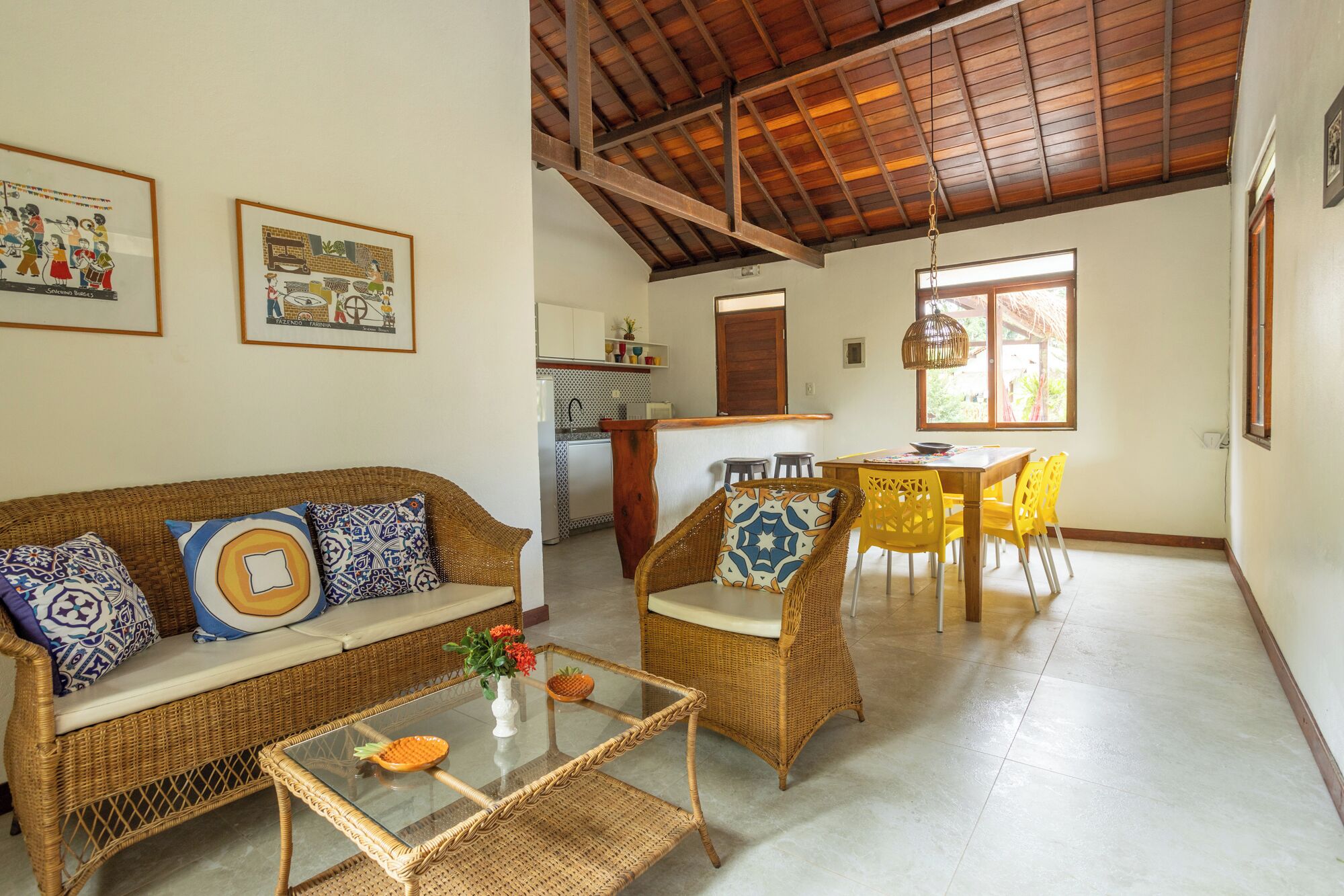 Una sala de estar con un sofá, una mesa de centro de vidrio y un comedor con mesa y sillas.