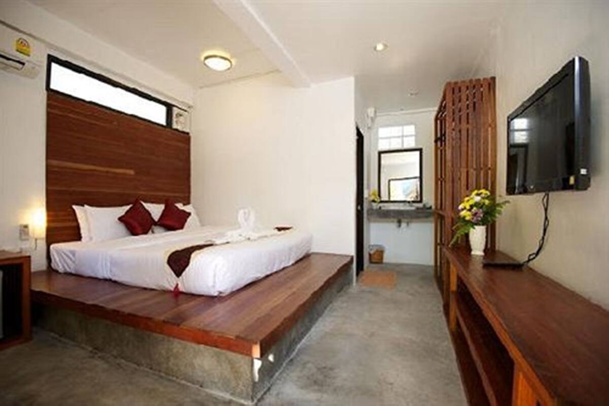 Ein Schlafzimmer mit einem Holzbett, einem Flachbildfernseher und einer kleinen Badeinheit.