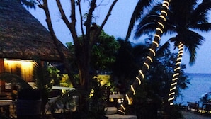 A pathway leading to a building with a thatched roof, surrounded by palm trees and string lights. - Fisherman Koh Tao (Koh Tao)