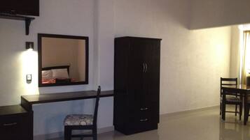 Una habitación de hotel con escritorio, silla, armario y espejo.