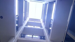Un corredor estrecho y cerrado con techo inclinado y ventanas grandes a ambos lados.