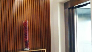 Un ascensor moderno con pantalla digital, un revestimiento de pared de madera y una pequeña mesa con un florero.