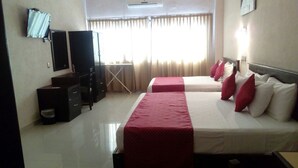 Una habitación de hotel con dos camas, un escritorio, una silla, un televisor y un equipo de aire acondicionado.