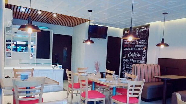 Interior de restaurante con mesas y sillas de madera, una barra y lámparas colgantes.
