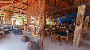 A spacious indoor area with wooden furniture, a bar area, and a decorative wall with a face mask.