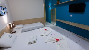 A hotel room with a bed, a TV, and a blue wall.