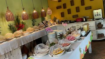 Disposição de buffet com diversos alimentos e uma luminária decorativa no teto.