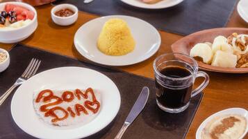 Una mesa de comedor con diversos platos, incluyendo arroz, pan y un plato con la inscripción 'Bom Dia'.