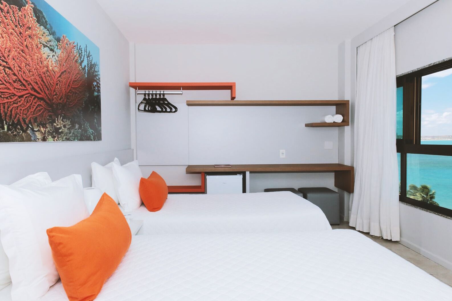 A modern hotel room with a large bed, a desk, and a view of the ocean.