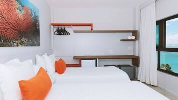 A modern hotel room with a large bed, a desk, and a view of the ocean.