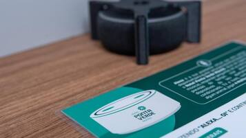 Uma placa verde e branca com o texto 'Ponta Verde' e um logotipo, colocada sobre uma superfície de madeira ao lado de um objeto preto.