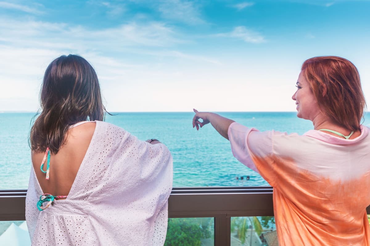 Two people overlooking a body of water from a balcony.
