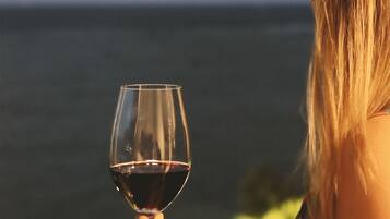 Una persona sosteniendo una copa de vino con vista al océano y una luna de fondo.