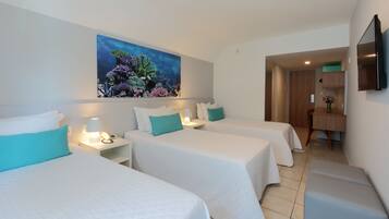 Habitación de hotel con dos camas, un cuadro de una escena submarina, un escritorio con una silla y un televisor montado en la pared.