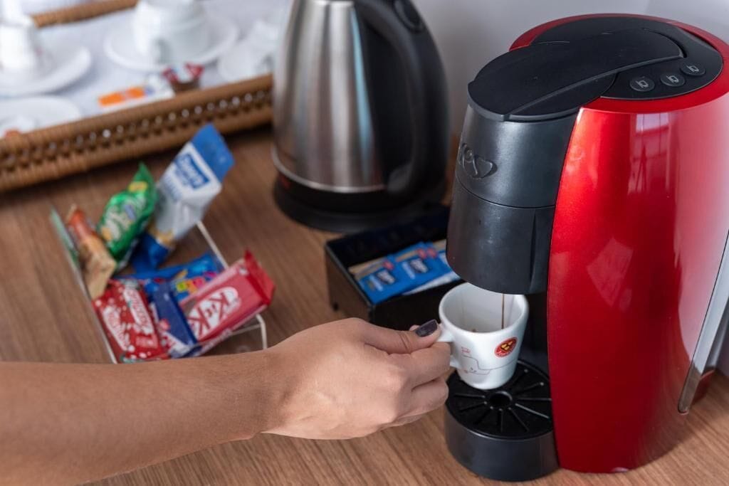 A red coffee machine with a single cup dispenser being used.