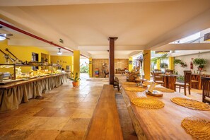 A long buffet table with food items and a wooden bench in the center. - Jeri Village Hotel (Jijoca de Jericoacoara)