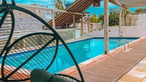 A poolside area with a hanging chair and a wooden deck. - Jeri Village Hotel (Jijoca de Jericoacoara)