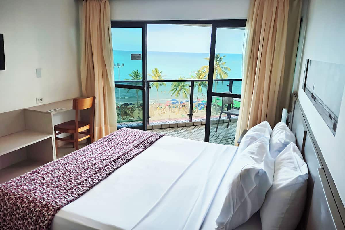 Une chambre d’hôtel avec un lit, un bureau et une vue sur la plage.