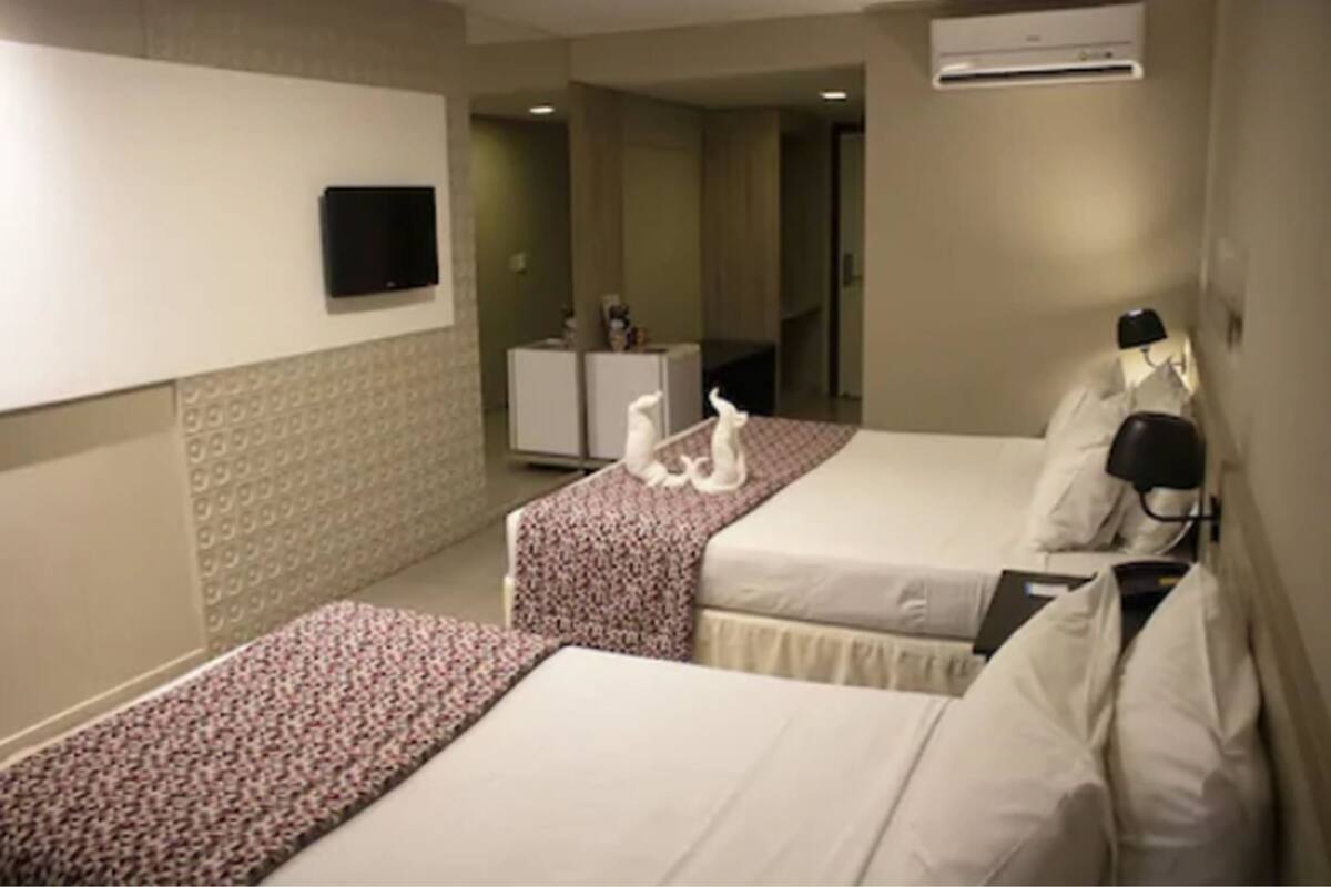 Une chambre d’hôtel avec deux lits, une télévision, un bureau et une armoire.