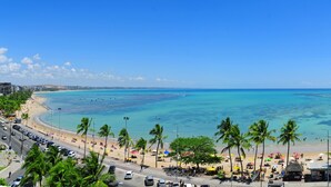 A beachside view with a road, parked cars, and palm trees. - Maceió Mar Hotel (Maceió)