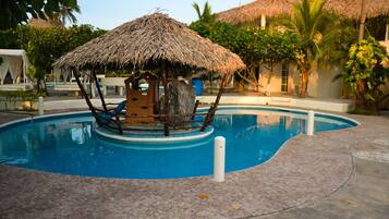 Relax by the serene pool surrounded by lush greenery and palm trees.