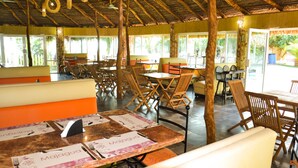 A restaurant with wooden furniture and a thatched roof. Tables are arranged for dining. - Bon Jesús Hotel (Tecolutla)