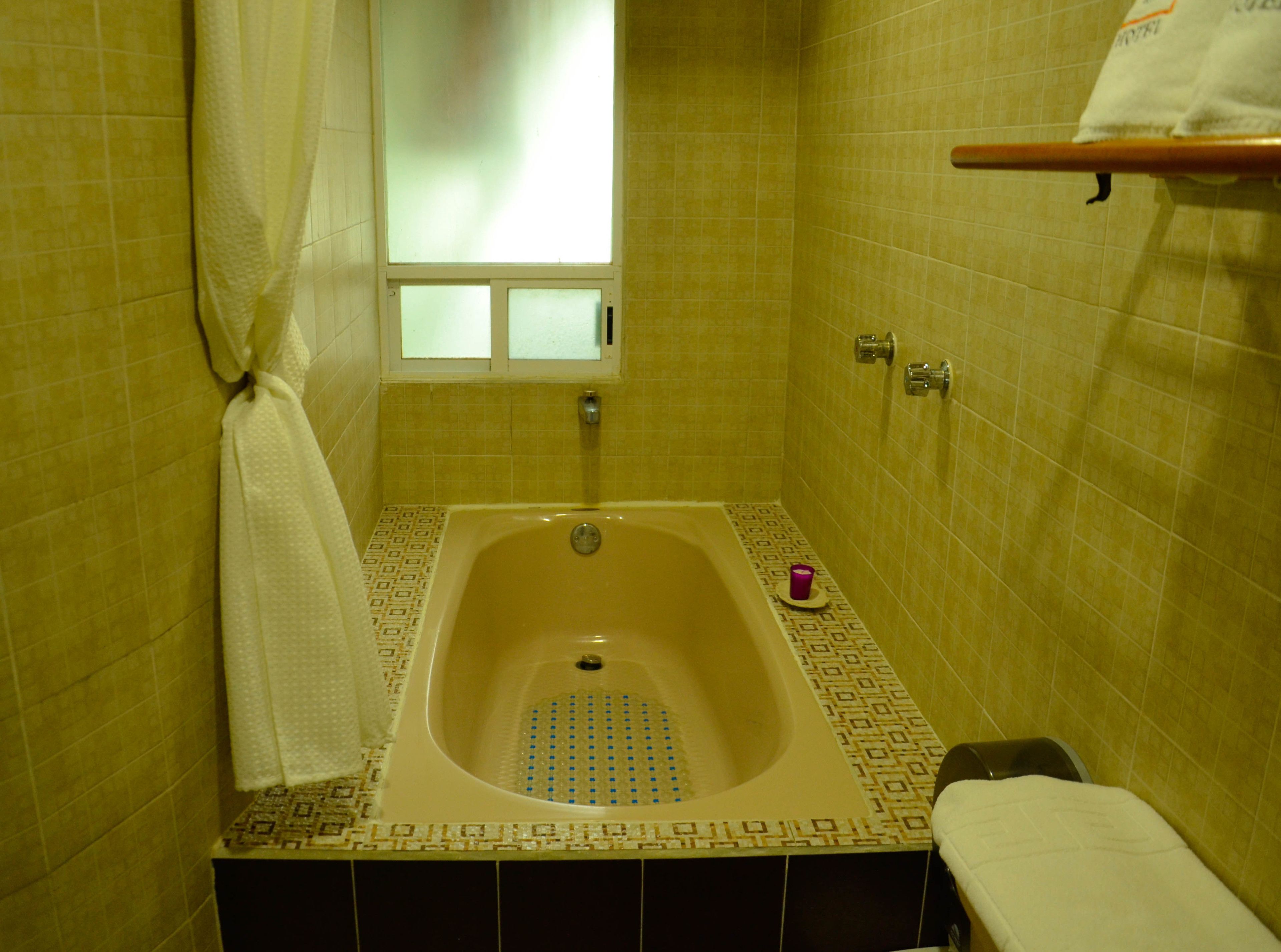 A bathroom with a bathtub, a window, and a towel rack.