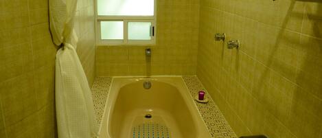 A bathroom with a bathtub, a window, and a towel rack.