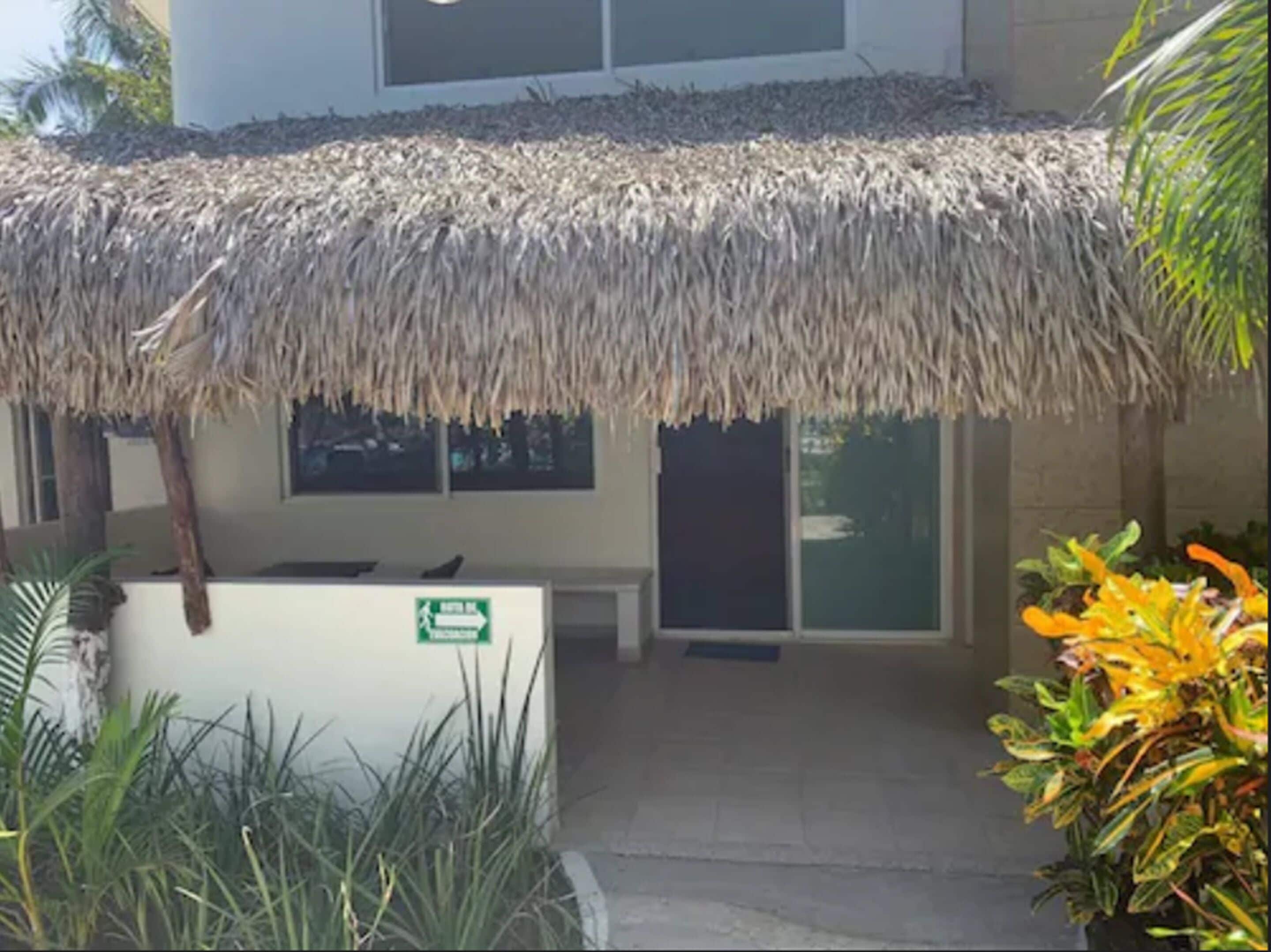 A building with a thatched roof entrance, a reception desk, and a sign indicating a direction.