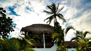 A building with a thatched roof, surrounded by lush tropical vegetation. - Bon Jesús Hotel (Tecolutla)