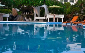 A swimming pool with clear blue water, surrounded by lounge chairs and a covered seating area. - Bon Jesús Hotel (Tecolutla)