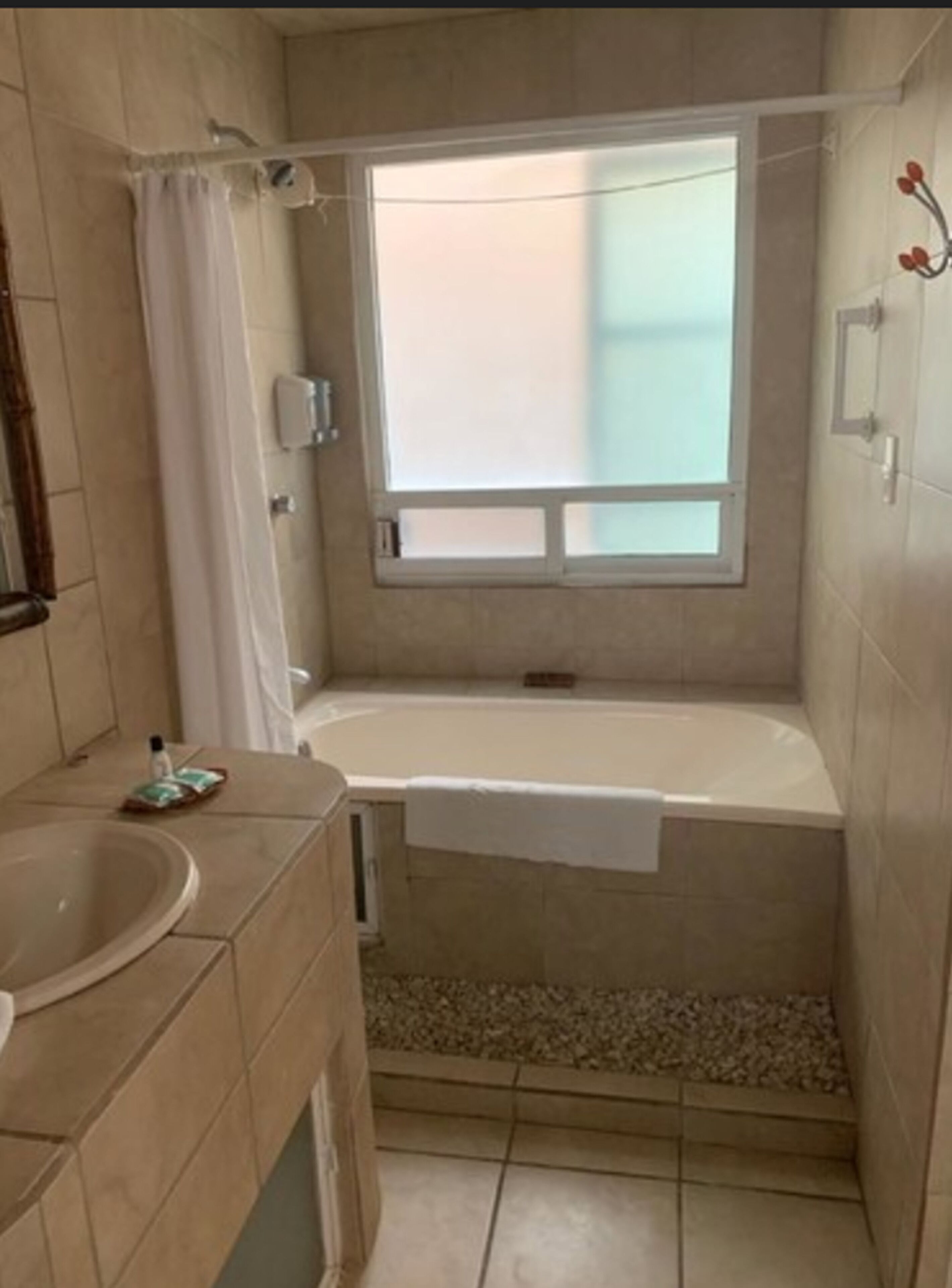 Une petite salle de bain avec une baignoire, une fenêtre et un lavabo.