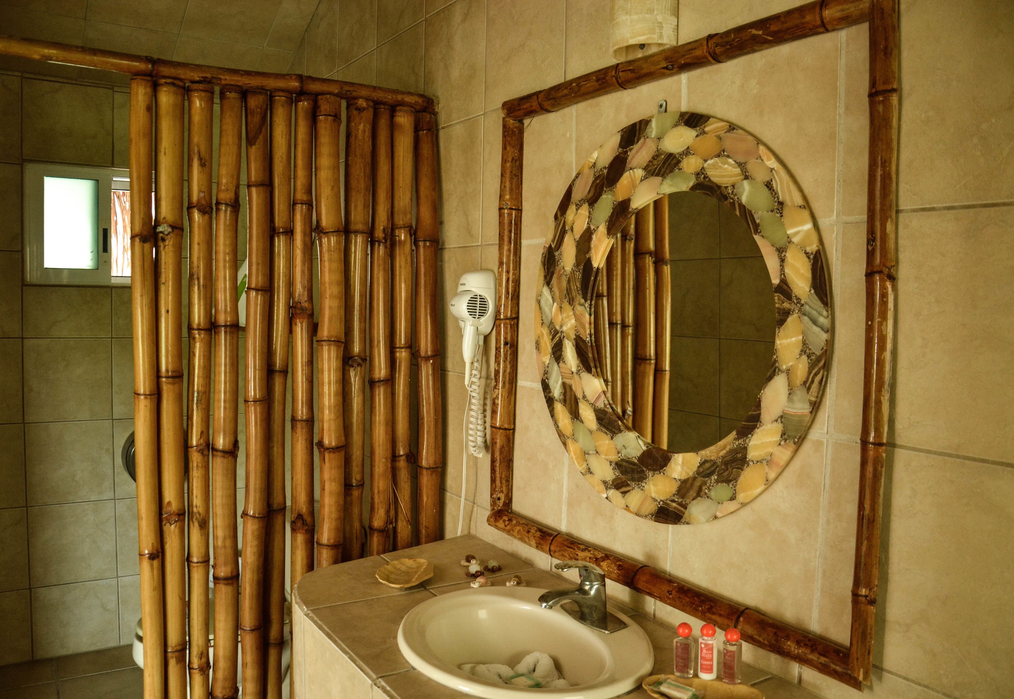 A bathroom with a bamboo partition, a sink with a mirror, and a hairdryer.