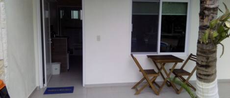 A room with a door marked '19', a small table with chairs, and a potted palm tree.