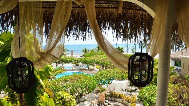 A tropical resort with a pool, lush greenery, and a view of the ocean. - Bon Jesús Hotel (Tecolutla)