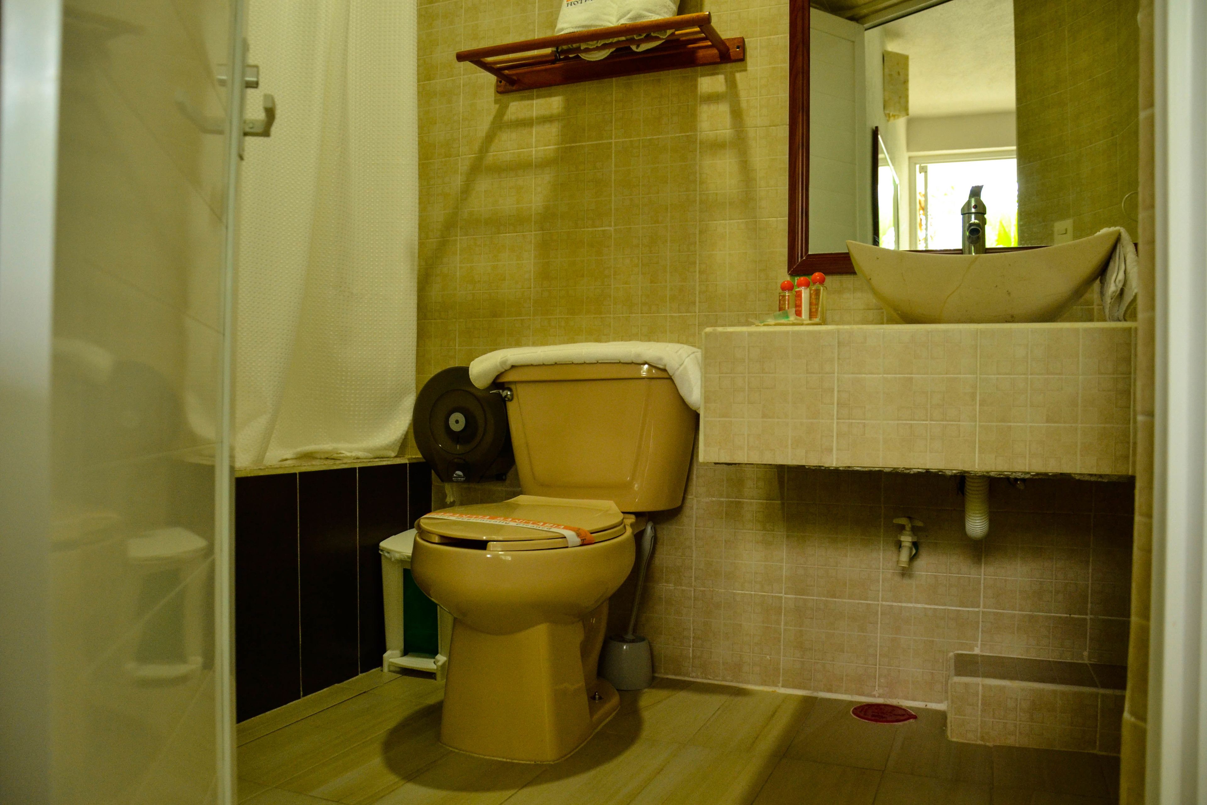 Et badeværelse med toilet, vask og spejl.