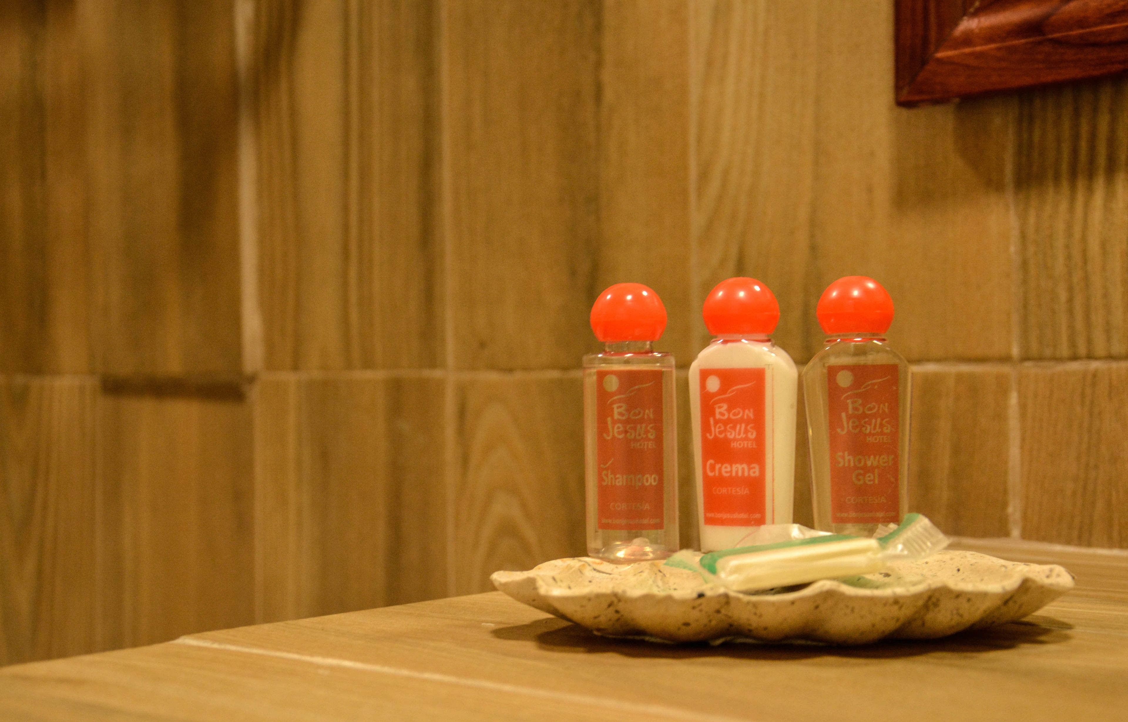 Trois flacons de shampoing, d’après-shampoing et de gel douche de l’hôtel Bon Jesus, présentés sur un plateau en céramique.
