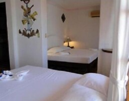 Una habitación de hotel con cama, mesita de noche y lámpara de pared.