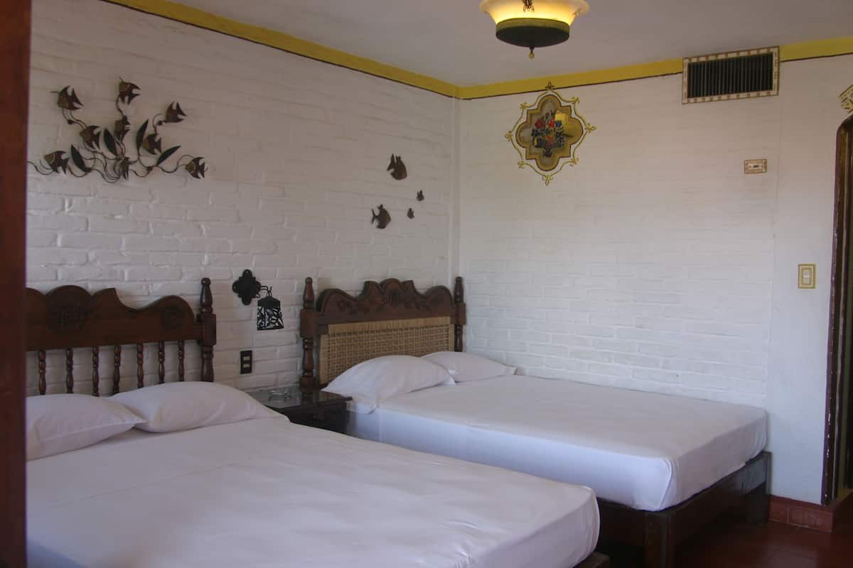 Ein Zimmer mit zwei Einzelbetten, weißen Wänden und einem Wandbild.