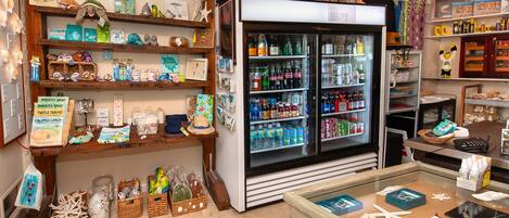 Un negozio con scaffali pieni di diversi articoli, una vetrina refrigerata e una cassa.