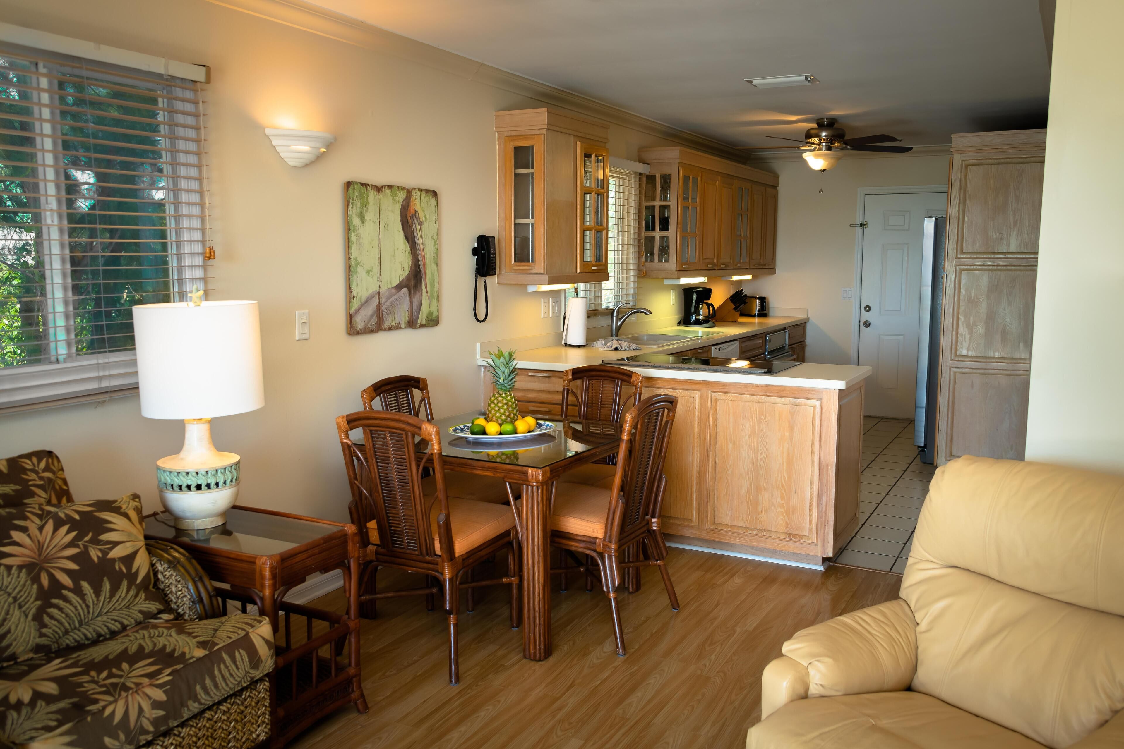 A kitchen with wooden cabinets, a dining table with chairs, a refrigerator, and a coffee maker.